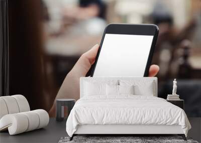 close-up on hand holding phone showing white screen on desk at coffee shop. Wall mural