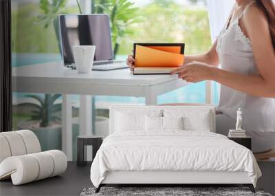 young woman wearing white see through pajamas sits and reads book to review lessons in morning to understand and learn lessons from books because exam time is near. concept of reading books to learn Wall mural