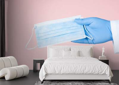 Hand in medical gloves hold medical protective mask. Wall mural