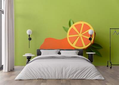 Spilled juice and paper orange fruit on green background. Copy space. Creative or art food concept Wall mural