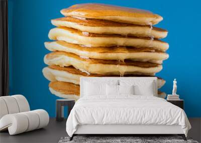 Stack of pancakes with honey decorated sweet cherry pinned on a fork on blue background Wall mural