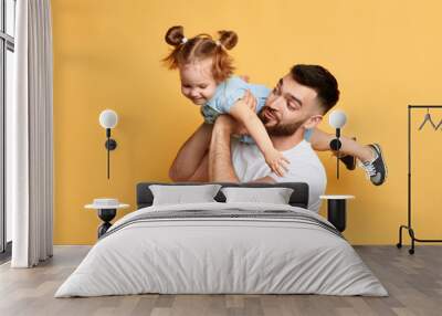 caring father holding, lifting his adorable child on yellow background. close up photo. funny time with dad. I love you. my daddy Wall mural