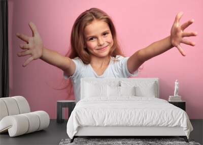 cheerful positive beautiful girl in white t-shirt with arms wide open looking at the camera, kid meeting her guests, welcome, kindness, friendship. close up portrait, isolated pink background Wall mural