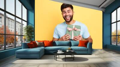 handsome bearded overjoyed man wearing casual clothes holding present box standing isolated over yellow background,Birthday party. celebration, happiness, best present from girlfriend Wall mural