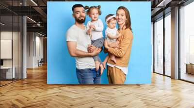 happy young couple and their kids posing to the camera. love, friendship concept. isolated blue background Wall mural