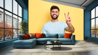 smiling cheerful young man showing two fingers up, victory sign. close up portrait, studio shot, body language, success, luck, happiness Wall mural