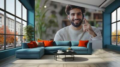 Cheerful millennial arabic male with beard calls by phone works with laptop at workplace points finger at empty space in office room interior Business client communication remotely at  : Generative AI Wall mural