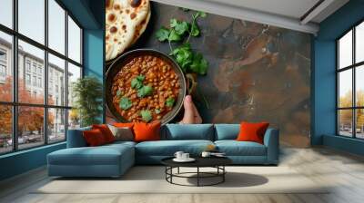 Female hands holding a bowl and eating traditional Indian Punjabi dish Dal makhani with lentils and beans served with naan flat bread fresh cilantro on brown concrete rustic table top  : Generative AI Wall mural