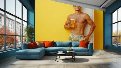 Full body fun young man wear shorts swimsuit glasses hold in hands beer bootle beach refrigerator relax near hotel pool isolated on plain yellow background Summer vacation sea rest sun : Generative AI Wall mural