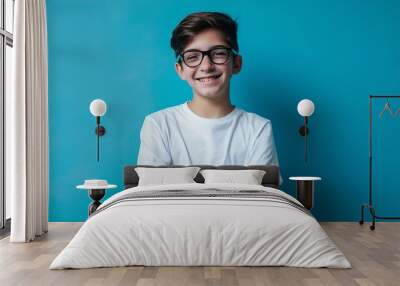 Portrait of smiling attractive teenage boy wearing eyeglasses with crossed arms looking at camera isolated on blue background Vision health care : Generative AI Wall mural