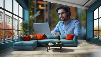 Side view of indian businessman in headphones working on laptop making video call sitting at desk having web conference with customer in office free space : Generative AI Wall mural