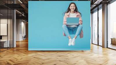 Young smiling Asian girl student floating in midair with using laptop isolated on blue studio copy space background : Generative AI Wall mural