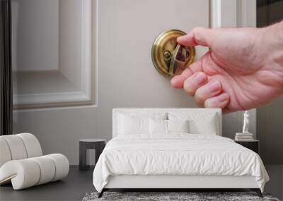 Close up of man locking deadbolt door lock on white entry door. Home security burglar and robbery prevention. Wall mural