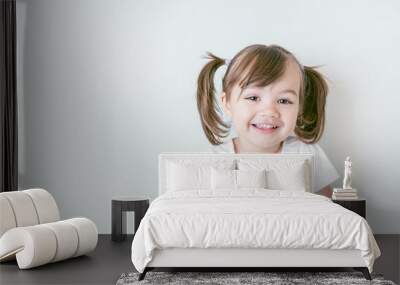 portrait of smiling baby girl with ponytails and in a white t-shirt Wall mural