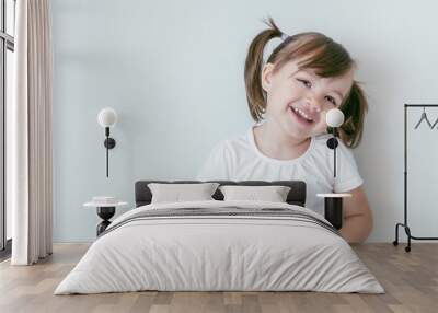 portrait of smiling baby girl with ponytails and in a white t-shirt Wall mural