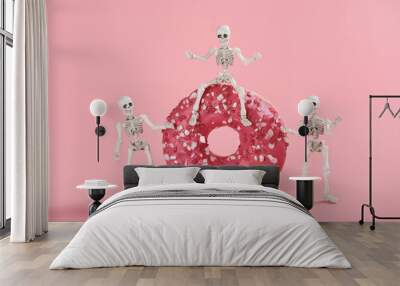 The skeleton sits astride a pink-glazed donut and two skeletons stand side by side. Bright image on a pink background for a Halloween party in a cafe Wall mural