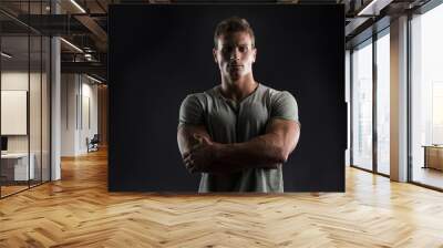 handsome muscular young man on dark with stern expression Wall mural