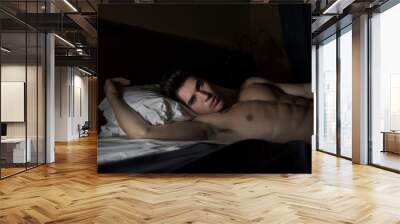 Handsome shirtless athletic young man in bed at night Wall mural