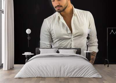 Handsome young man in white shirt and jeans posing isolated on black background in studio Wall mural