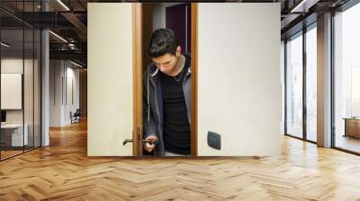 Handsome young man opening door to enter Wall mural