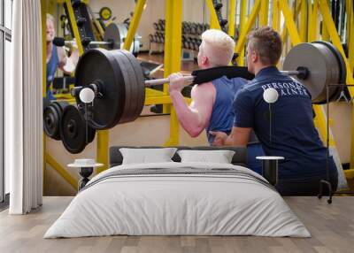 personal trainer helping client in gym Wall mural