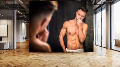 Shirtless muscular handsome man looking at himself in bathroom mirror in the morning Wall mural