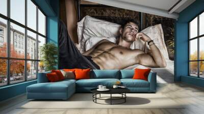 Shirtless sexy male model lying alone on his bed Wall mural