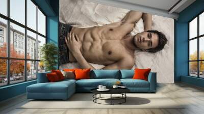 Shirtless sexy male model lying alone on his bed Wall mural