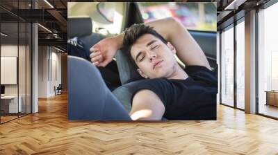 Young man sleeping inside his car, exhausted Wall mural