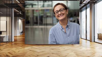 Business woman at work. Portrait of successful businesswoman entrepreneur smiling and looking at camera. Middle aged woman wearing glasses and striped shirt Wall mural