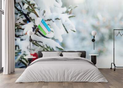 Christmas Uzbekistan. Xmas tree covered with snow, decorations and a flag of Uzbekistan. Snowy forest background in winter. Christmas greeting card. Wall mural