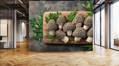 Sliced morel mushrooms displayed on a wooden board with fresh herbs Wall mural