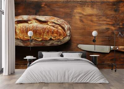 Whole sourdough loaf on a wooden surface with a knife nearby Wall mural