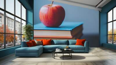 Books in a colorful stack with an apple on top, close-up, neutral background, emphasizing learning and tradition Wall mural