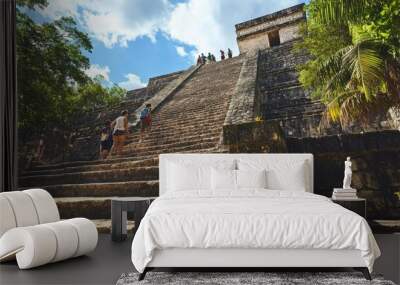 The grand staircase leading up to El Castillo at Chichen Itza, with tourists ascending the steps. Wall mural