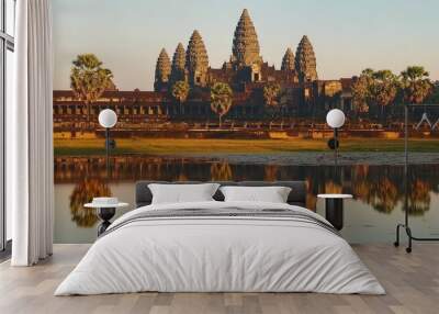 The iconic image of Angkor Wat at sunrise, with the temple reflecting in the moat and surrounded by palm trees. Wall mural