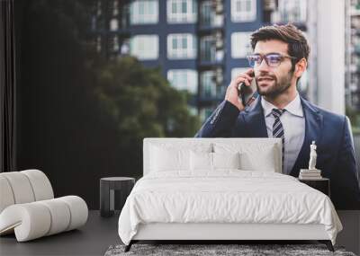 Caucasian businessman in a suit using smartphone talking while outside the office. Wall mural