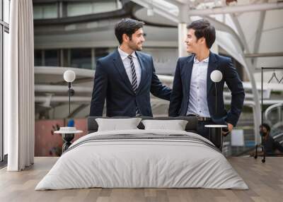 caucasian businessman talking to asia businessman colleague while walking outside the office. Wall mural