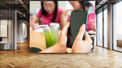 Mockup image women hands holding mobile phone with blank black screen in busy restaurant Wall mural