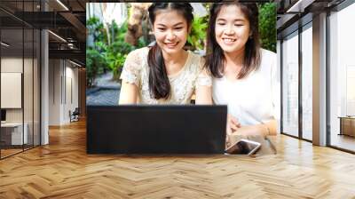 Pretty young couple women talking together and use laptop computer in outdoor park Wall mural