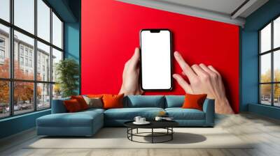 A person is holding a phone with a white screen and pointing at it Wall mural