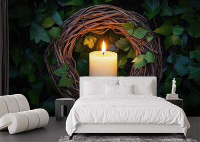 A candle is lit in a wreath of green leaves Wall mural