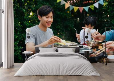 Asian man enjoy eating BBQ together with family at yard. Wall mural