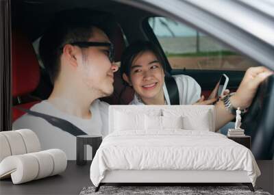 Couple traveler sit inside a car using map application on smartphone. Wall mural