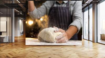 female chef is kneading dough on a wooden surface, sprinkling it with flour Wall mural