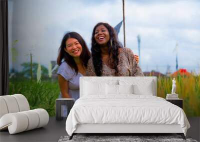 Asian Chinese girl and black Afro American woman exploring together exotic tropical village on fresh rice field enjoying holidays trip as girlfriends tourism fun Wall mural