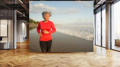 fit and attractive middle aged woman running on the beach - 40s or 50s mature lady with grey hair doing hard jogging workout enjoying fitness and healthy lifestyle Wall mural