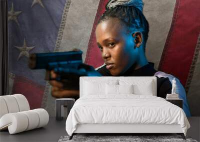 Hollywood movie style portrait of young attractive and confident black African American woman holding gun as special federal agent isolated in USA flag background Wall mural