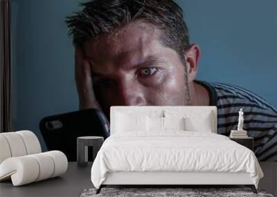 isolated close up face portrait of young attractive and stressed man using mobile phone feeling worried and frustrated looking anxious while reading bad news Wall mural