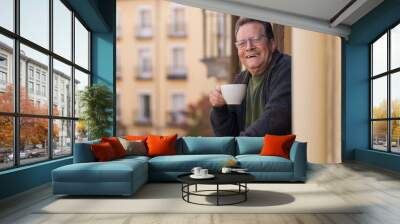 lifestyle portrait of happy and cheerful mature man 65 to 70 years old at home balcony feeling positive and relaxed drinking coffee enjoying retirement smiling to the street view Wall mural